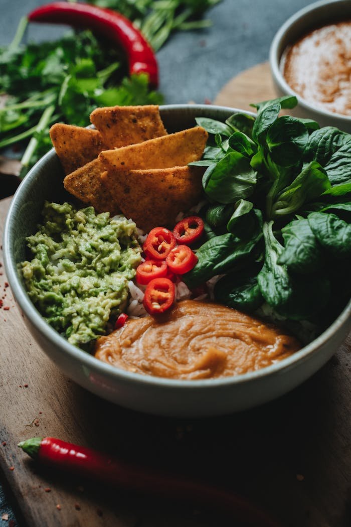 Services A delicious vegan rice bowl topped with guacamole, chili peppers, and fresh greens.
